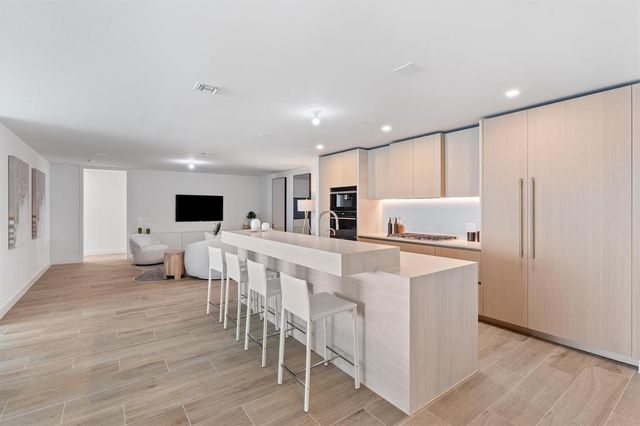 a living room with stainless steel appliances furniture and a flat screen tv