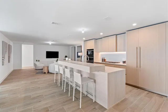 a living room with stainless steel appliances furniture and a flat screen tv