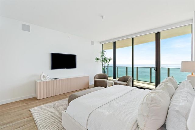 a bedroom with a large bed and a flat tv screen on dresser