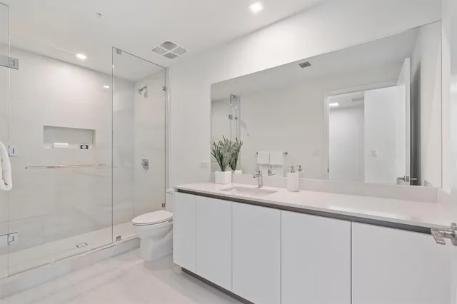a bathroom with a double vanity sink toilet mirror and shower
