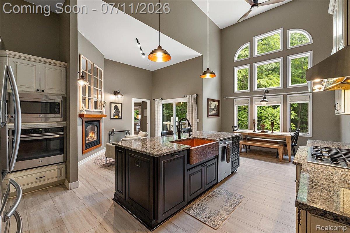 4219 Gardner Road Metamora, MI 48455 - Photo 18 of 87 Open-concept kitchen and living area featuring high vaulted ceilings, extensive window array, a central island with a copper farmhouse sink, and integrated stainless steel appliances