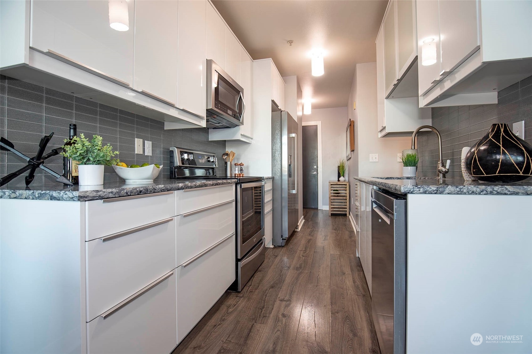 655 Crockett Street, Unit B304 Seattle, WA 98109 - Photo 13 of 35 a kitchen with stainless steel appliances granite countertop a refrigerator a sink dishwasher and a stove with wooden floor