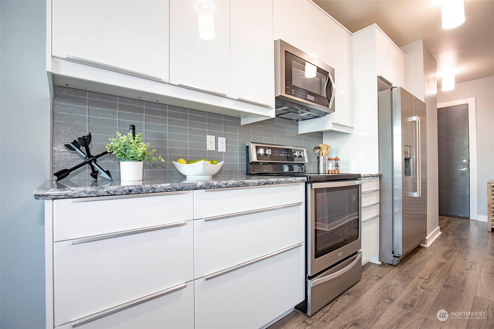 655 Crockett Street, Unit B304 Seattle, WA 98109 - Photo 14 of 35 a kitchen with stainless steel appliances granite countertop a refrigerator a stove and a wooden floor
