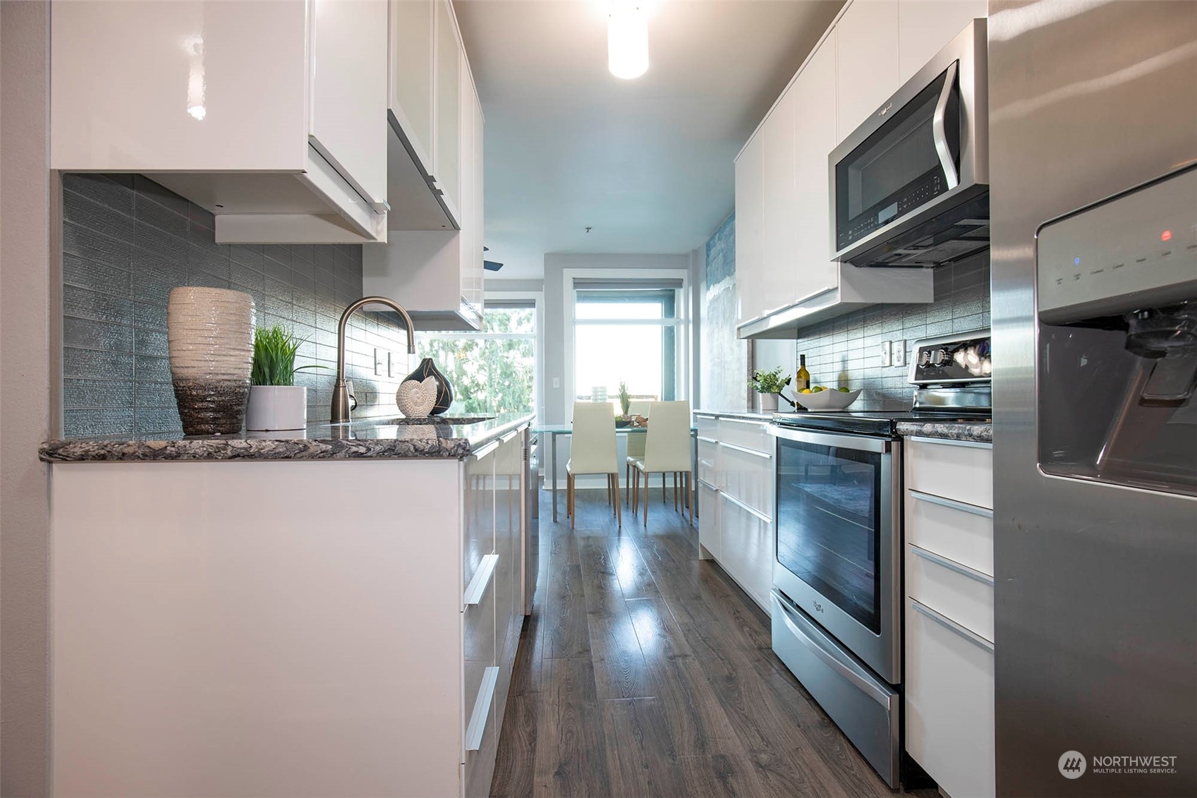 655 Crockett Street, Unit B304 Seattle, WA 98109 - Photo 18 of 35 a kitchen with stainless steel appliances granite countertop a refrigerator a sink dishwasher a stove and white countertops with wooden floor
