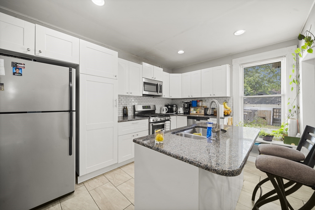 3 Cleveland Street Springfield, MA 01104 - Photo 3 of 14 a kitchen with stainless steel appliances granite countertop a refrigerator a stove a sink a dining table and chairs