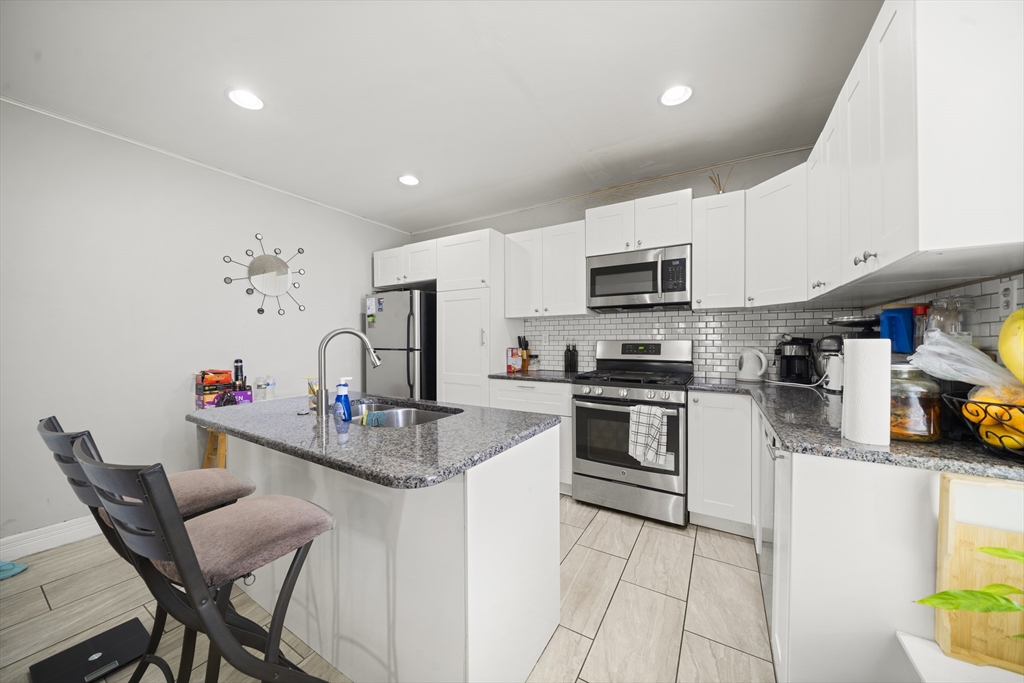 3 Cleveland Street Springfield, MA 01104 - Photo 4 of 14 a kitchen with stainless steel appliances granite countertop a stove top oven a sink a dining table and chairs