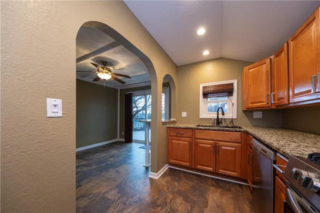 a kitchen with stainless steel appliances granite countertop a sink a stove and a wooden floors