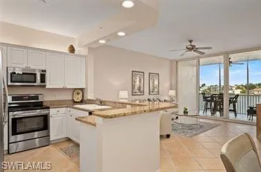 a kitchen with stainless steel appliances kitchen island granite countertop a refrigerator a stove a sink a dining table and chairs with wooden floor