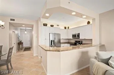 a large white kitchen with a lot of white cabinets and stainless steel appliances