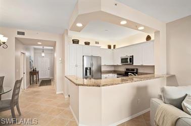 450 Launch Circle, Unit 203 Naples, FL 34108 - Photo 6 of 23 a kitchen with stainless steel appliances kitchen island granite countertop a refrigerator a stove a sink a dining table and chairs with wooden floor