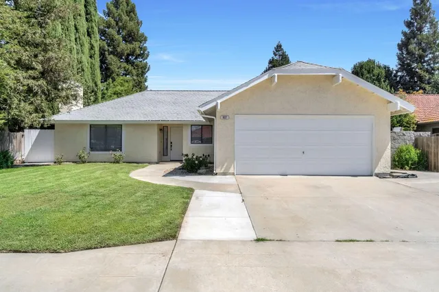 a view of a house with a yard plants and a garage
