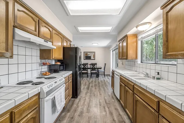 a kitchen with a stove a sink a refrigerator and chairs