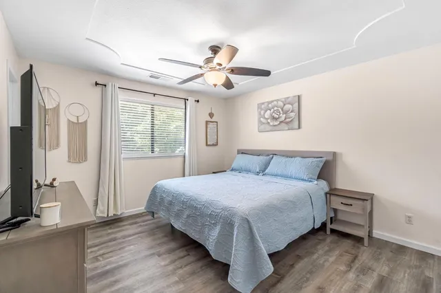 a bedroom with a bed a flat screen tv and a dresser