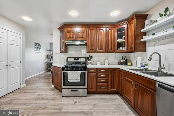 a kitchen with stainless steel appliances granite countertop a stove a sink dishwasher and a microwave oven with wooden cabinets