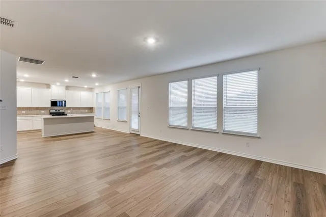 a view of an empty room with a window and wooden floor