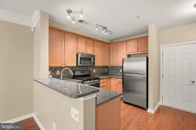 a kitchen with stainless steel appliances granite countertop a refrigerator a stove a sink and a microwave