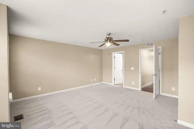 a view of an empty room with a chandelier fan