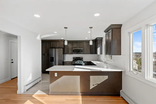 a large kitchen with stainless steel appliances a large counter top a stove and a wooden floors