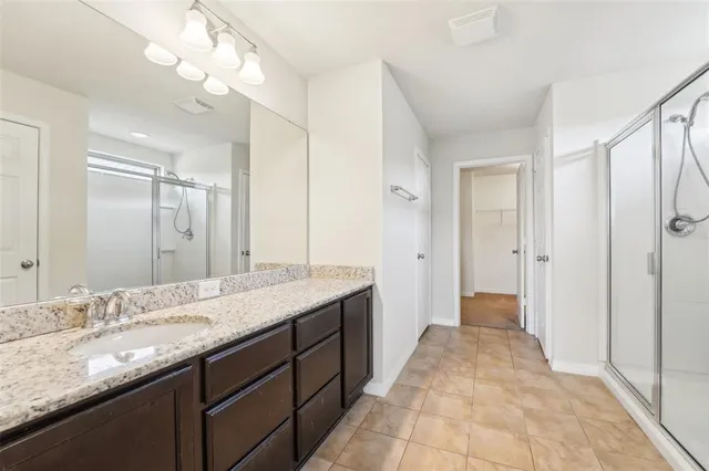 a spacious bathroom with a granite countertop sink a mirror and a shower