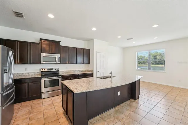 a large kitchen with stainless steel appliances granite countertop a sink stove and refrigerator