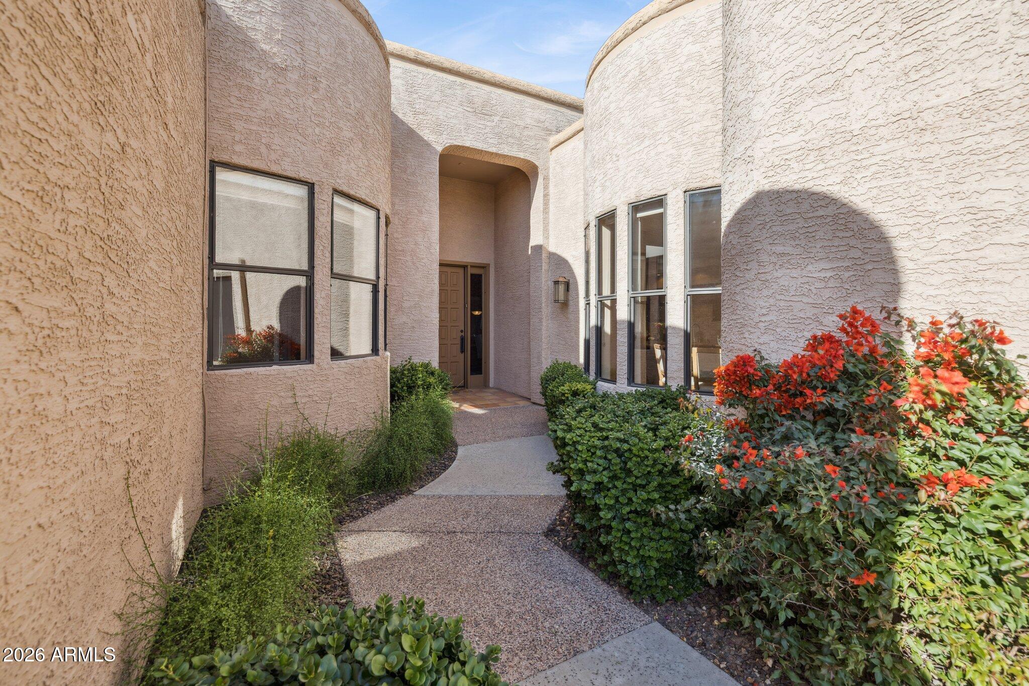 8100 East Camelback Road, Unit 129 Scottsdale, AZ 85251 - Photo 9 of 13 a front view of a house with a yard and flowers