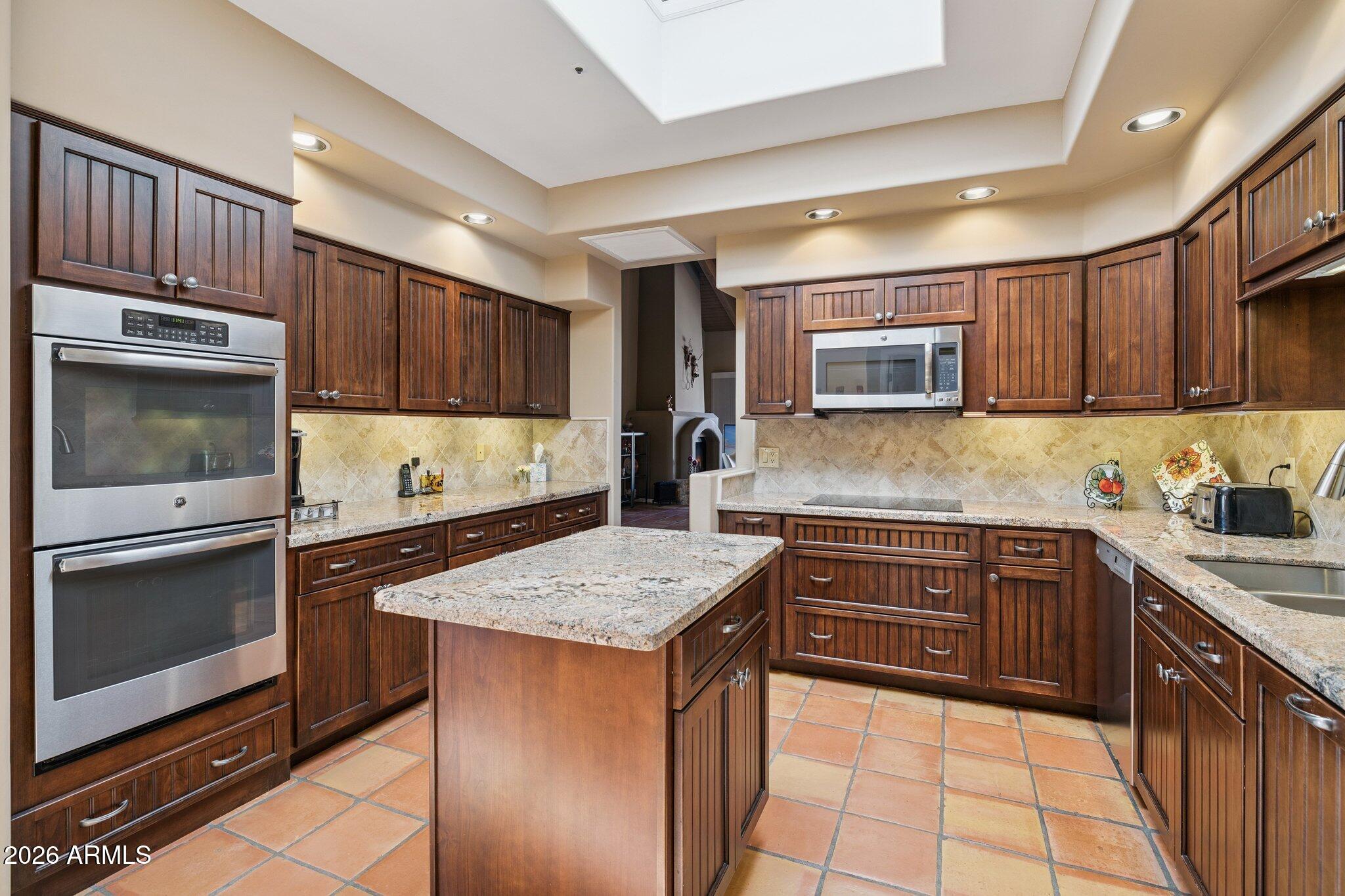 8100 East Camelback Road, Unit 129 Scottsdale, AZ 85251 - Photo 3 of 13 a kitchen with stainless steel appliances granite countertop wooden cabinets microwave and stove