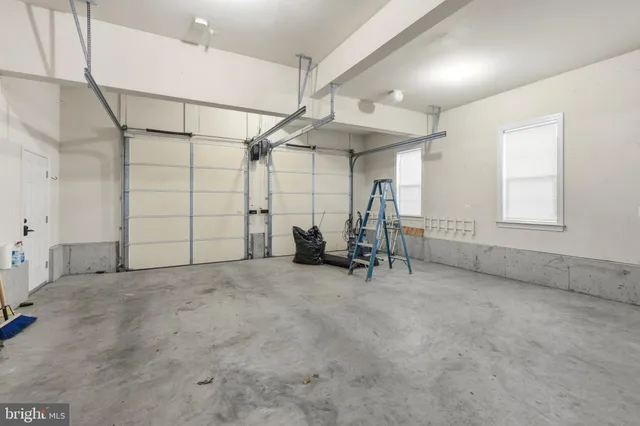 an empty room with chandelier fan and windows