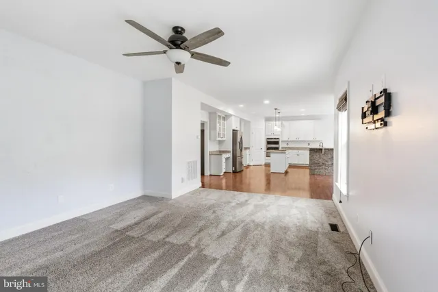 a large room with chandelier fan and wooden floor