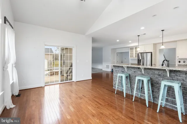 a open kitchen with dining table wooden floor and a refrigerator