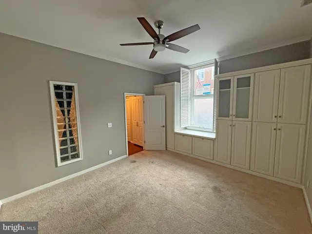 an empty room with closet and a chandelier fan