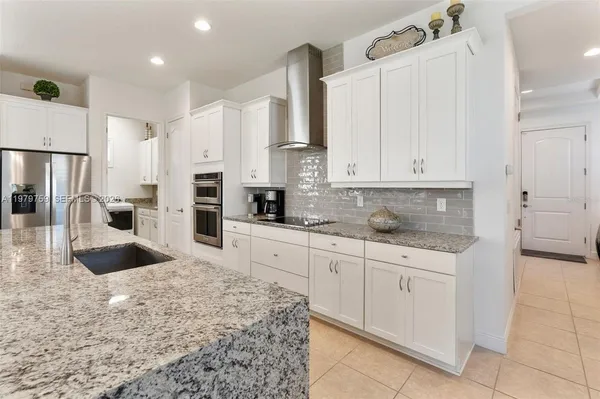 a view of a kitchen with granite countertop white cabinets and stainless steel appliances