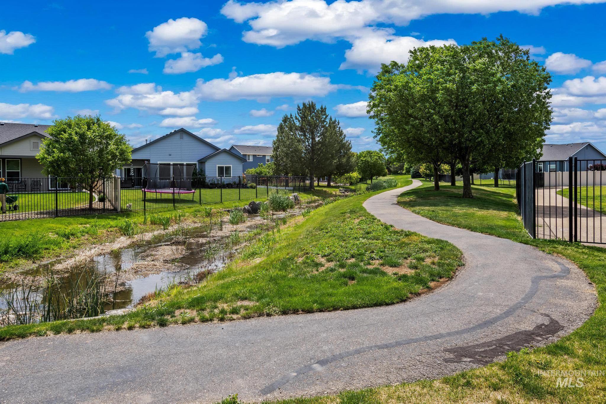 2681 East Rhyolite Court Nampa, ID 83686 - Photo 47 of 48 Winding paved pathway bordered by green lawns and mature trees, featuring a water feature and residential structures in the background