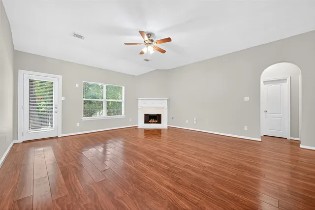 a view of an empty room with wooden floor and a window