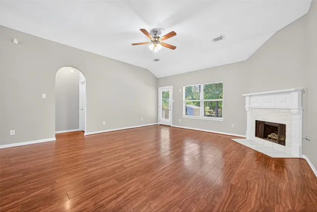 a view of an empty room with wooden floor fireplace and a window