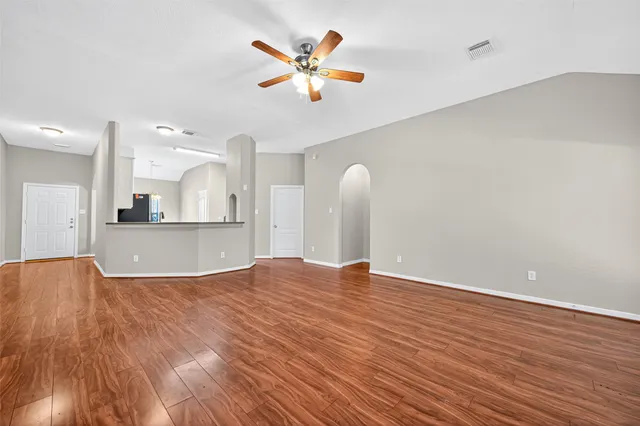a view of kitchen and empty room with wooden floor