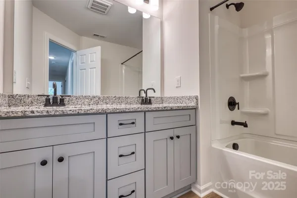 a bathroom with a granite countertop tub sink and mirror