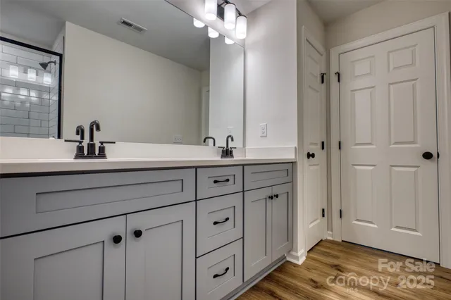 a bathroom with a double vanity sink a mirror and a shower