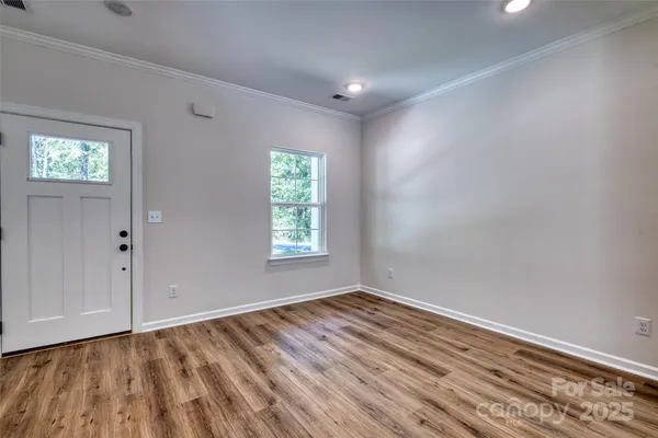 a view of an empty room with wooden floor and a window