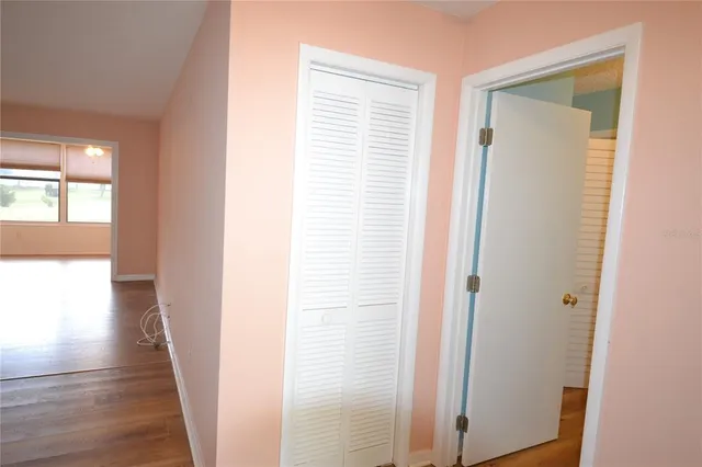 a view of a hallway with wooden floor and closet