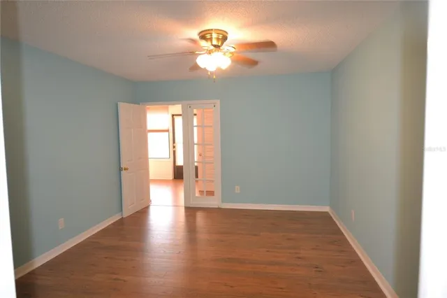 a view of an empty room with window and wooden floor