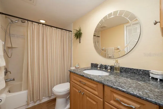 a bathroom with a granite countertop sink mirror vanity and toilet