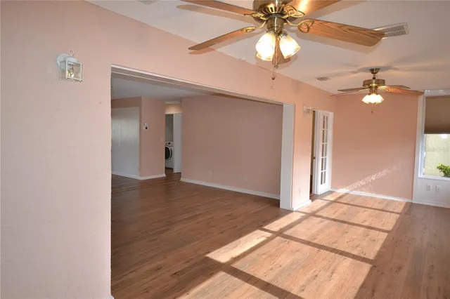 a view of an empty room with window and wooden floor