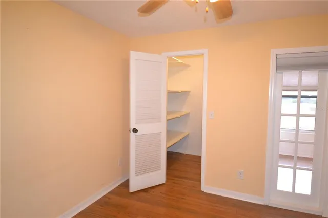 an empty room with wooden floor cabinet and windows