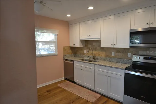 a kitchen with granite countertop white cabinets and white appliances