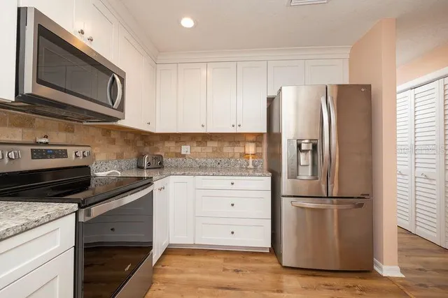 a kitchen with appliances a refrigerator and cabinets