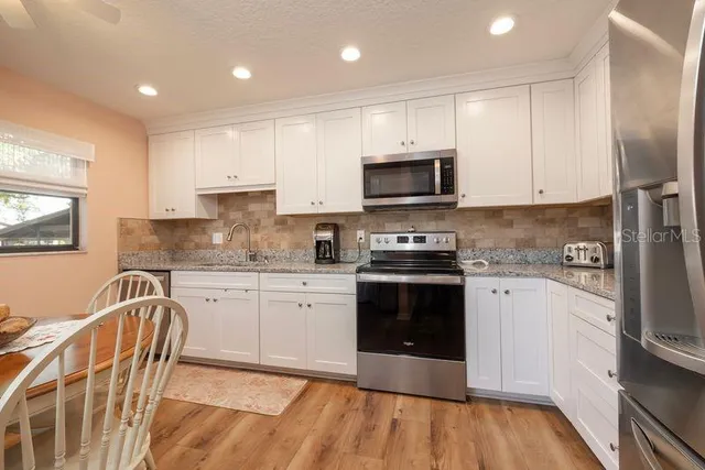 a kitchen with granite countertop a stove top oven microwave and cabinets