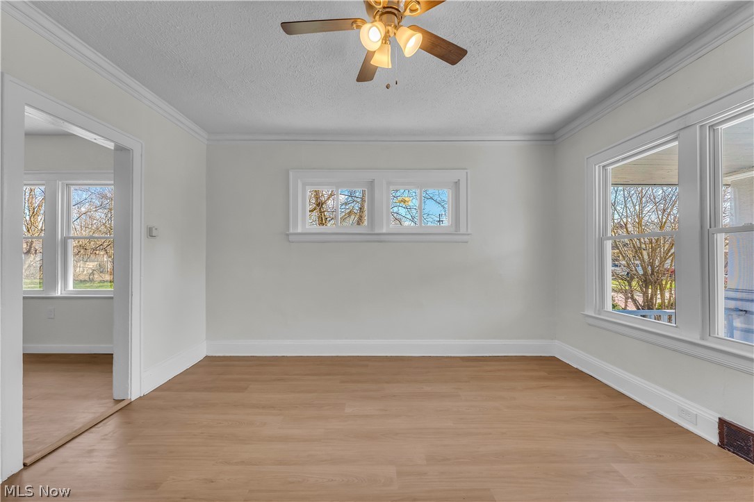 12905 Watterson Avenue Cleveland, OH 44105 - Photo 5 of 30 Empty room featuring ceiling fan, light wood finished floors, a textured ceiling, plenty of natural light, and ornamental molding