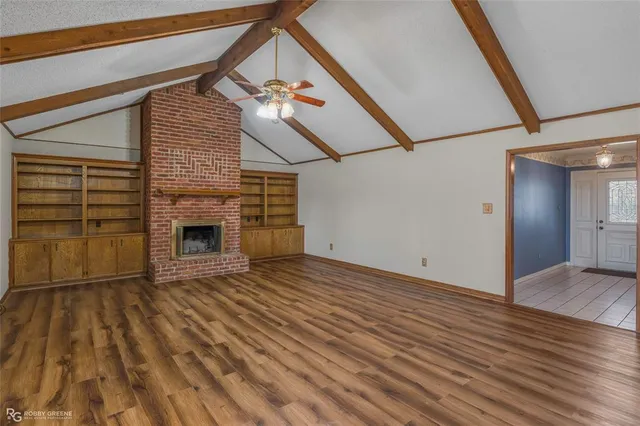 a view of empty room with wooden floor and fireplace