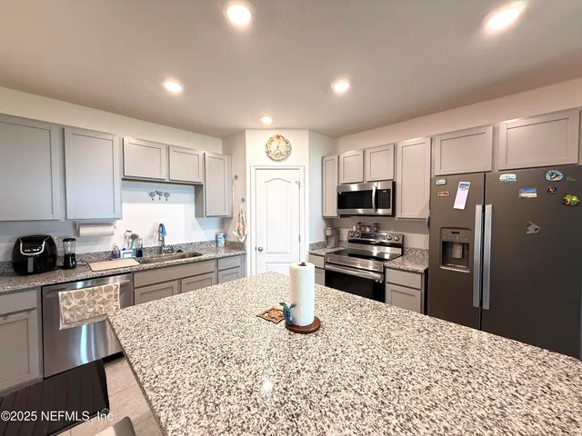 a kitchen with stainless steel appliances granite countertop a refrigerator stove microwave and sink