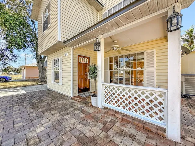 a view of an empty room with wooden floor and a ceiling fan